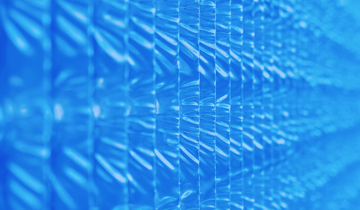 Close-up of a blue, translucent plastic sheet with a ribbed, repeating rectangular pattern and soft reflections.